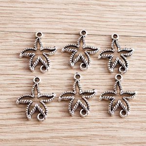 Set of six silver starfish pendants with twisted rope texture on a wooden background