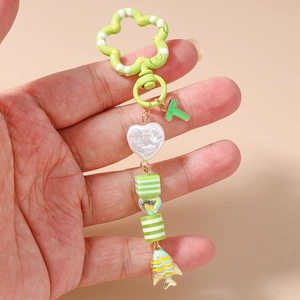 Détail d'un porte-clés poisson vert avec perles rayées et breloque en lettre T dorée