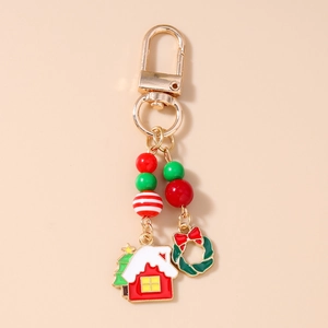 Détail d'un porte-clés de Noël avec breloques dorées, perles rouges et couronne verte