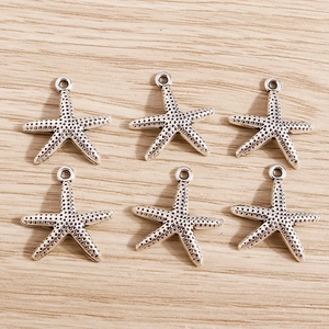 Detailed view of six vintage silver starfish charms for DIY jewelry making and crafts