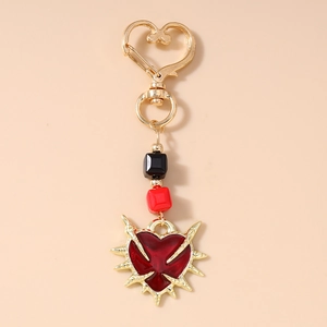 Gothic heart keychain with thorn detail, black beads, and gold hardware on pink background