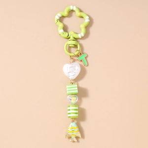 Détail d'un porte-clés poisson doré vert avec perles rayées et fermoir fleur en métal vert
