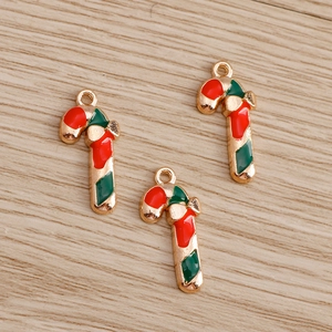 Macro detail of three red and green enamel candy cane charms with gold-plated finish