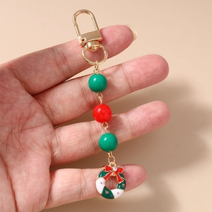Close-up of a Christmas wreath keychain with red bow, green beads and gold hardware