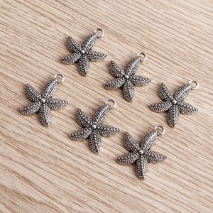 Macro view of six antique silver starfish pendants with textured grain on wood