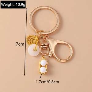 Détail macro du porte-clés doré avec pendentif cacahuète et médaillon caractère Fu