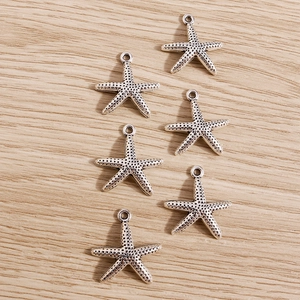 Macro detail of six silver starfish charms featuring antique finish and zinc alloy texture
