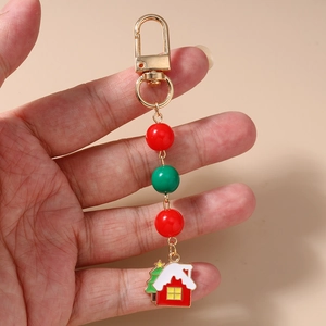 Detailed macro of festive Christmas house and tree enamel keychain with red beads