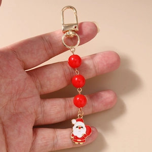 Detail of Christmas keychain featuring Santa Claus enamel charm and red beads held in hand