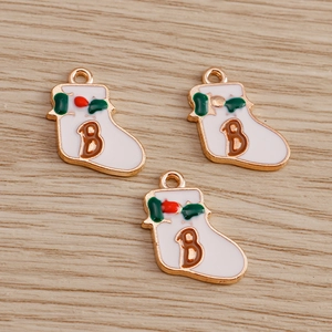 Detailed close-up of white enamel Christmas sock pendants with letter B and festive holly