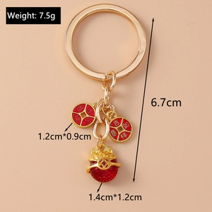 Détail de breloques porte-bonheur en émail rouge avec motifs dorés sur un porte-clés