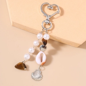 Détail d'un porte-clés bohème en coquillage avec perles et fermoir en forme de cœur