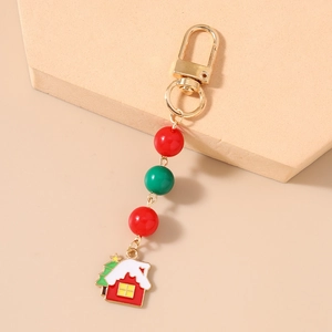 Detail of a Christmas house keychain with red and green beads on a warm beige background