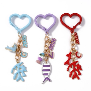 Three ocean-themed heart keychains with 2026 year pendants, dolphins, fish, and corals