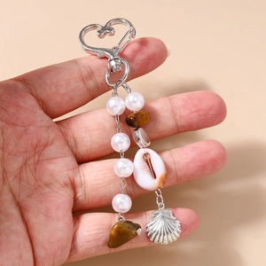 Détail des breloques coquillage et perles sur l'accessoire porte-clés en forme de cœur