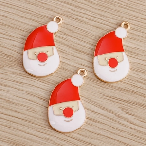 Three Santa Claus enamel charms with red hats and white beards on a wood background