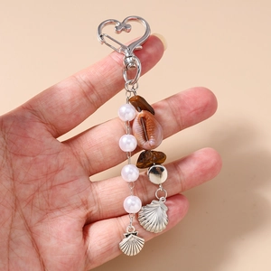 Détails d'un porte-clés bohème avec clip cœur, perles, coquillage et pierres naturelles