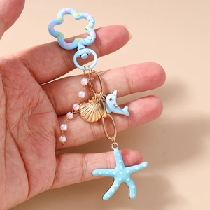 Détail du porte-clés étoile de mer bleue et perles tenu en main pour la taille