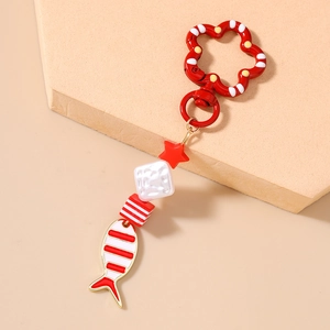 Close-up of red and white enamel fish pendant with star beads on a floral spring clasp