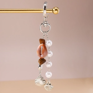 Détail du porte-clés bohème avec conque naturelle, perles blanches et coquillages