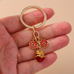 Porte-clés doré avec breloques porte-bonheur, perles rouges et motif chat en main