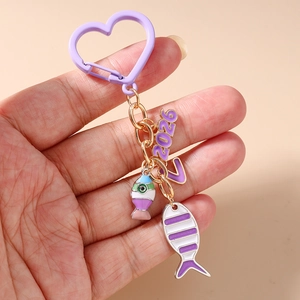 Close-up of purple 2026 charm keychain with enamel fish and fishbone pendant detail