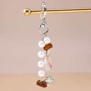 Détail d'un porte-clés bohème avec perles blanches, pierres naturelles et coquillages