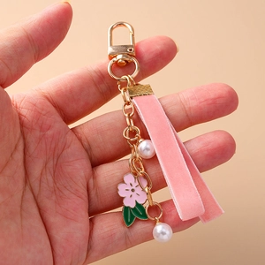 Pink velvet cherry blossom keychain with gold hardware and white pearls held in hand