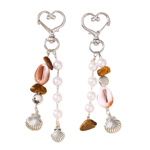 Porte-clés tendance avec perles, breloques coquillage et fermoir coeur sur fond blanc
