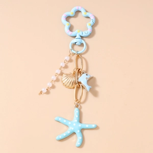 Détail d'un porte-clés océan avec perles, coquillage doré, dauphin et pendentif étoile de mer