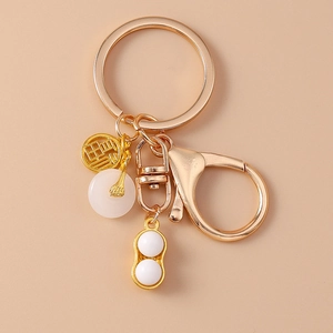 Détail du porte-clés doré avec charme caractère Fu, pendentif cacahuète et pierre