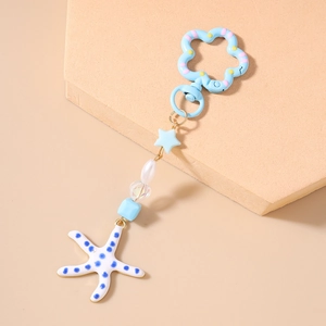 Detail van zeester sleutelhanger met blauwe bloemsluiting en harskralen met stippen
