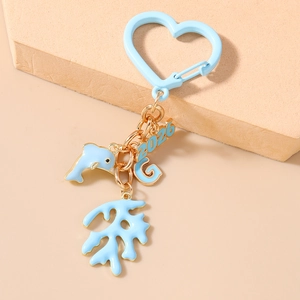 Detail of light blue enamel dolphin and year 2026 charms on golden heart keychain