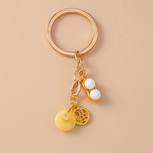 Détail d'un porte-clés doré avec breloque en cacahuète et pendentif caractère Fu