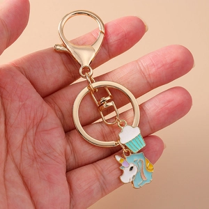 Goldener Einhorn und Cupcake Schlüsselanhänger mit Emaille-Anhängern in der Hand