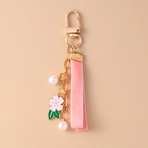 Detailed close-up of a pink velvet ribbon cherry blossom keychain with gold hardware