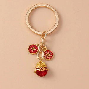 Détail d'un porte-clés Maneki Neko doré avec des pendentifs de pièces de chance rouges