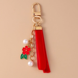 Detail of red floral keychain with velvet ribbon, golden spring hook and faux pearls