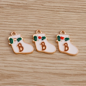Close-up of white enamel Christmas stocking charms with letter B and red berry detail