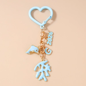 Detailed view of blue dolphin and coral charms with 2026 G pendants on heart keychain