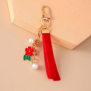 Detail of red velvet ribbon keychain with gold flower pendant and white pearls charms