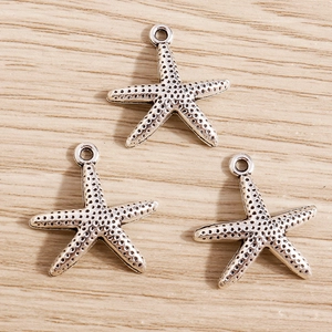 Macro detail of starfish pendants with antique silver texture on wood background