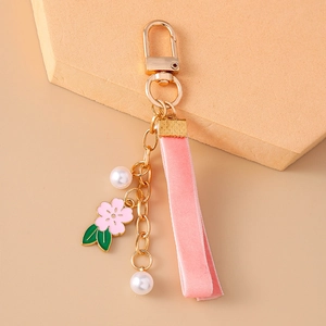 Close-up of a pink velvet ribbon keychain with cherry blossom charm and white pearls