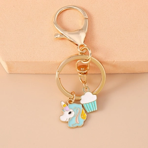 Detailansicht der goldfarbenen Schlüsselanhänger mit Einhorn und Cupcake Emaille-Anhängern
