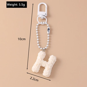 Detail view of white flower letter H keychain showing dimensions and weight metrics