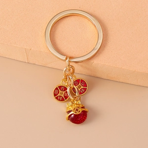 Détail du porte-clés doré avec pièces porte-bonheur et pendentif Maneki Neko rouge