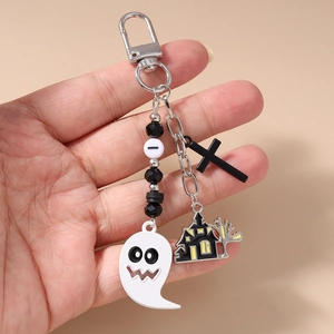 Close-up of Halloween keychain with ghost and haunted house charms held in hand