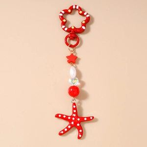 Detail van een rode ster en zeester sleutelhanger met stippen en parels aan de hanger