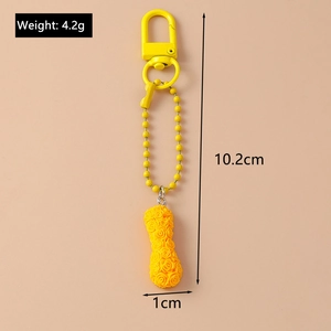 Detail view of yellow rose keychain with dimension labels and lobster clasp on orange background