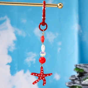 Zeester sleutelhanger met rode polkadots en gouden kralen op een metalen standaard